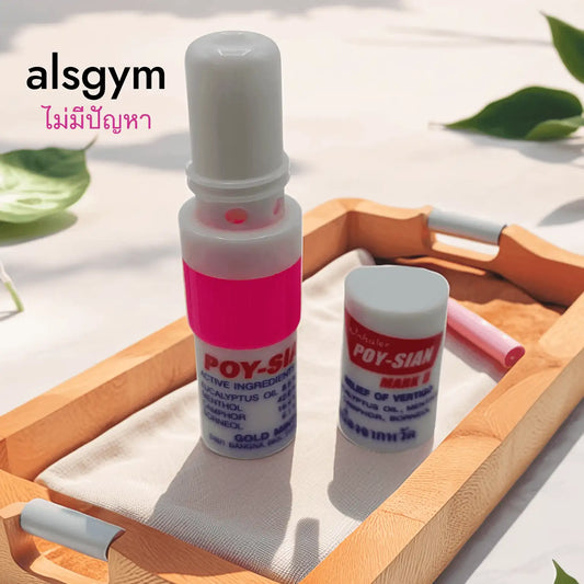 A small bottle labeled "alsgym" with a cap sits on a wooden tray, placed on a fabric mat with green leaves. The Poy-Sian Thai Herbal Nasal Inhaler – Gold Mint Formula is known for its effective nasal congestion relief. Thai text elegantly adorns the space above the tray.